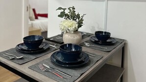 A dining area with a table set for four, a vase with flowers, and a TV displaying the word "NETFLIX" on the wall.