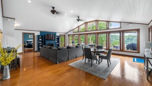 A spacious living area with a large gray sectional sofa, a dining table with chairs, and a kitchen area in the background. - 💦 Grande Villa – Lake Cumberland View • Game Room • Walk to Boat Ramp ➠ 389 (Somerset)