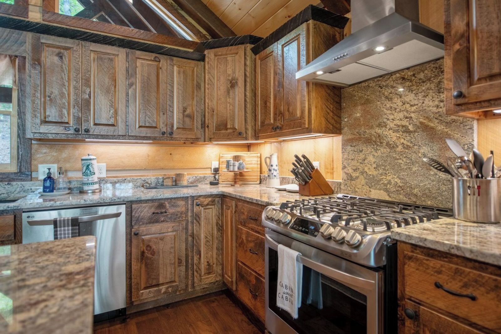 A modern kitchen with wooden cabinets, granite countertops, a gas stove, and a dishwasher.