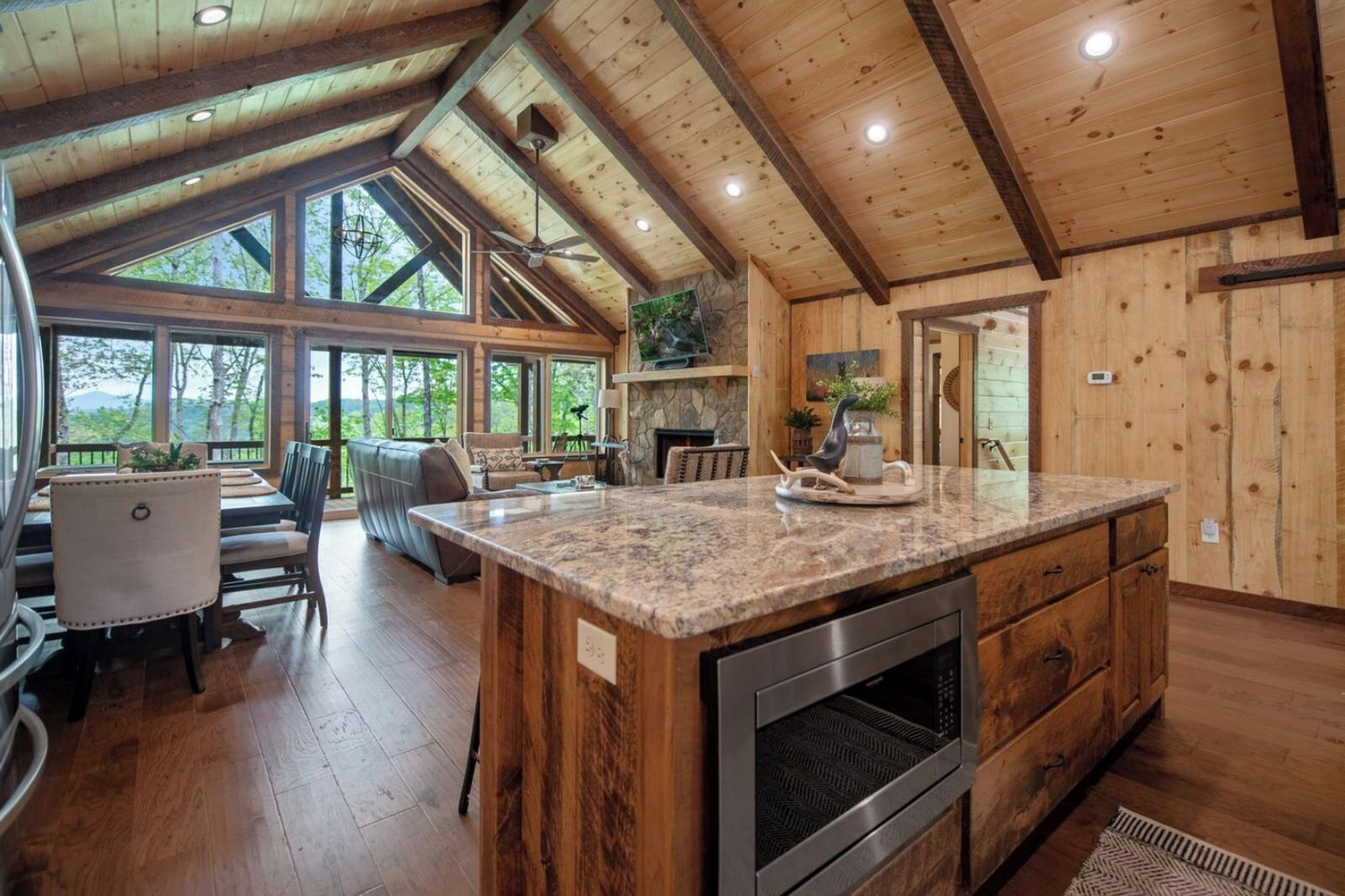 Una cocina amplia con una isla grande, vigas de madera y una chimenea de piedra.