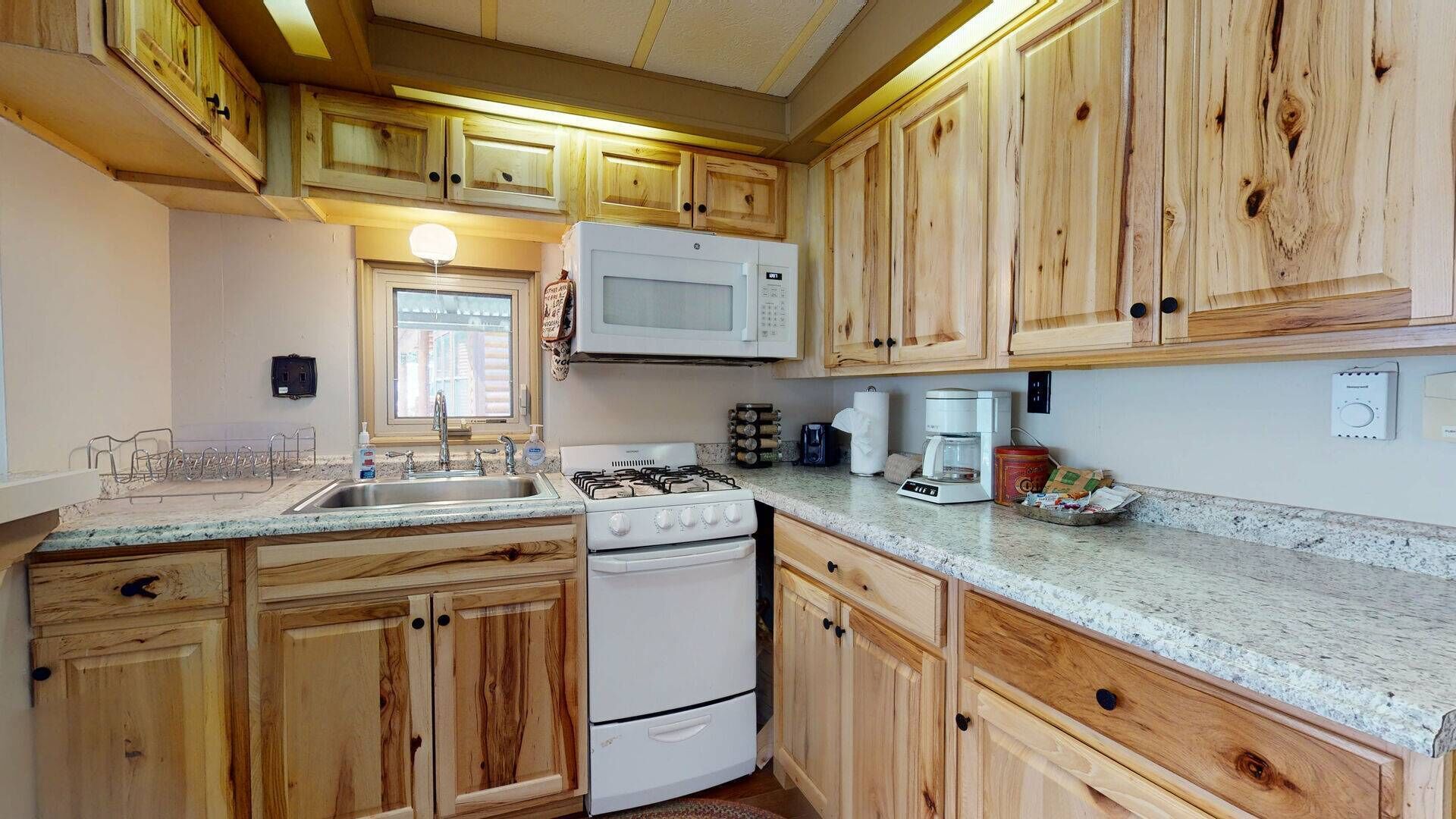 A kitchen with wooden cabinets, a white stove, a microwave, and a coffee maker.