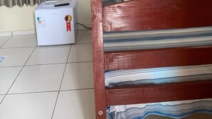 A room with a wooden bed, a white refrigerator, and a television mounted on the wall. - Pousada BG Lençóis (Barreirinhas)