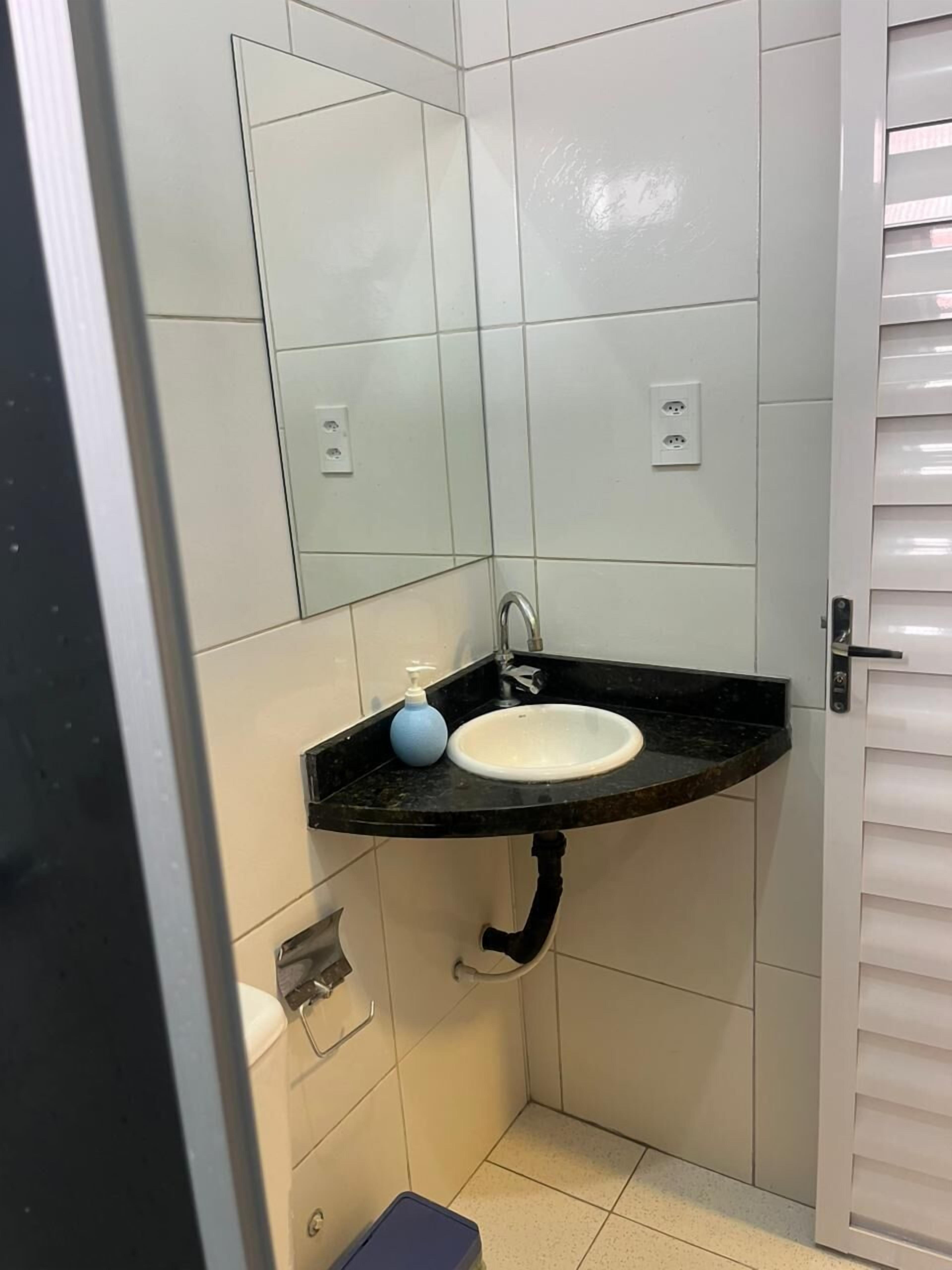 A small bathroom with a white sink, a mirror, and a black countertop.