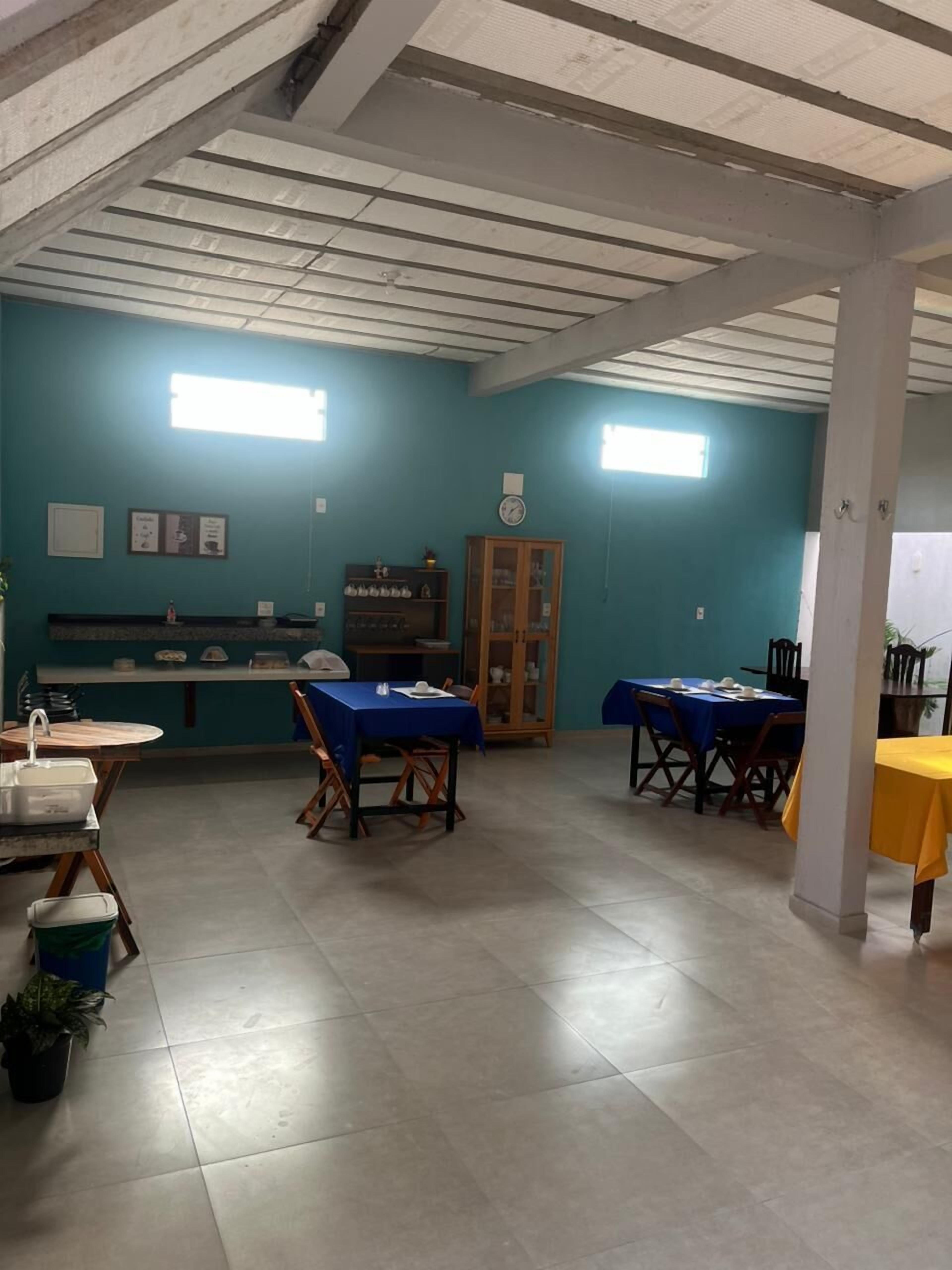 Un espace repas avec des tables et des chaises, un comptoir avec un évier et une horloge au mur.