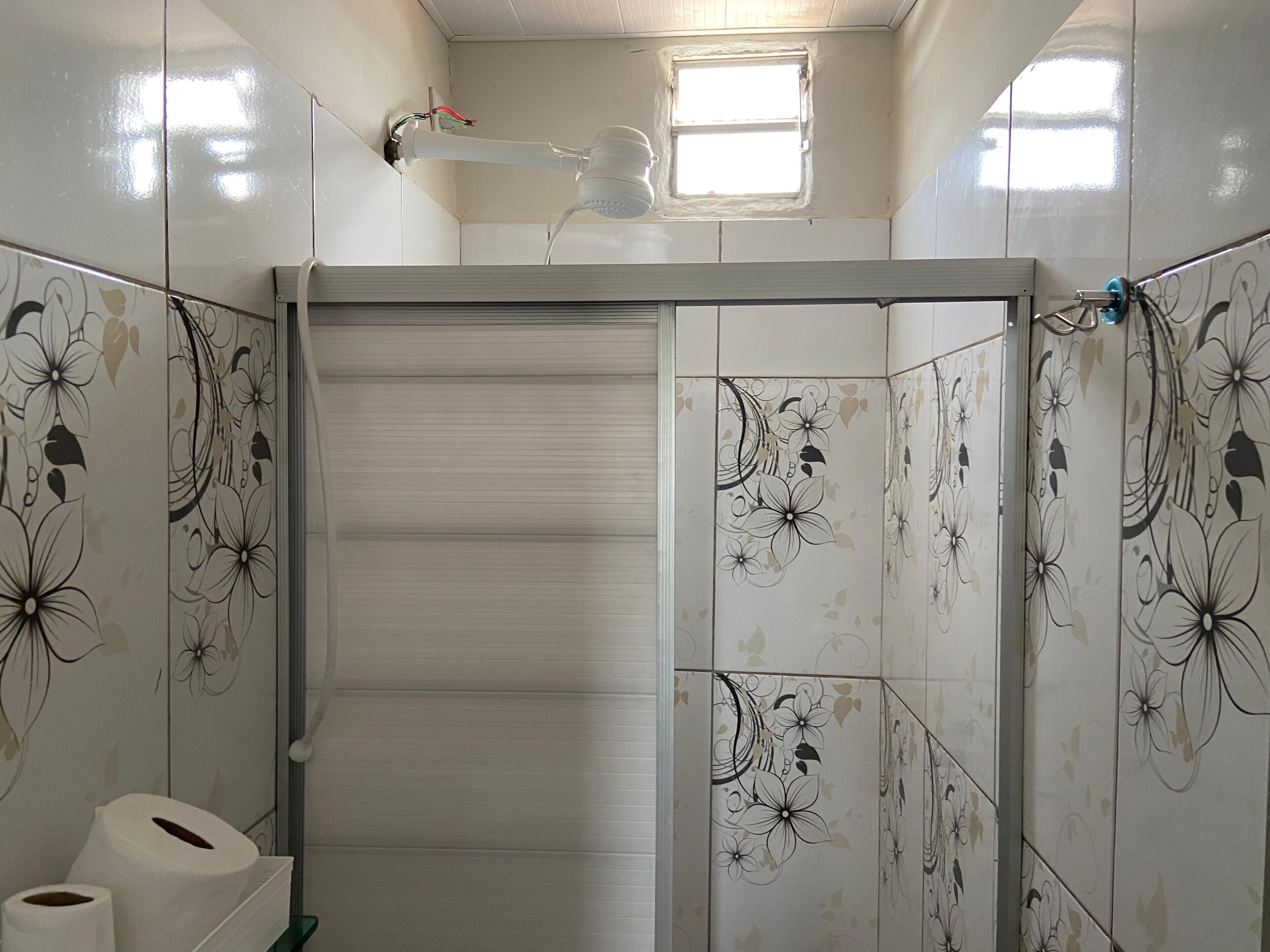 Un bagno con piastrelle a motivi floreali, un portasciugamani e una finestra.