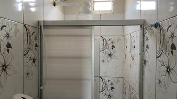 Un baño con baldosas de estampado floral, un dispensador de papel higiénico y una ventana.