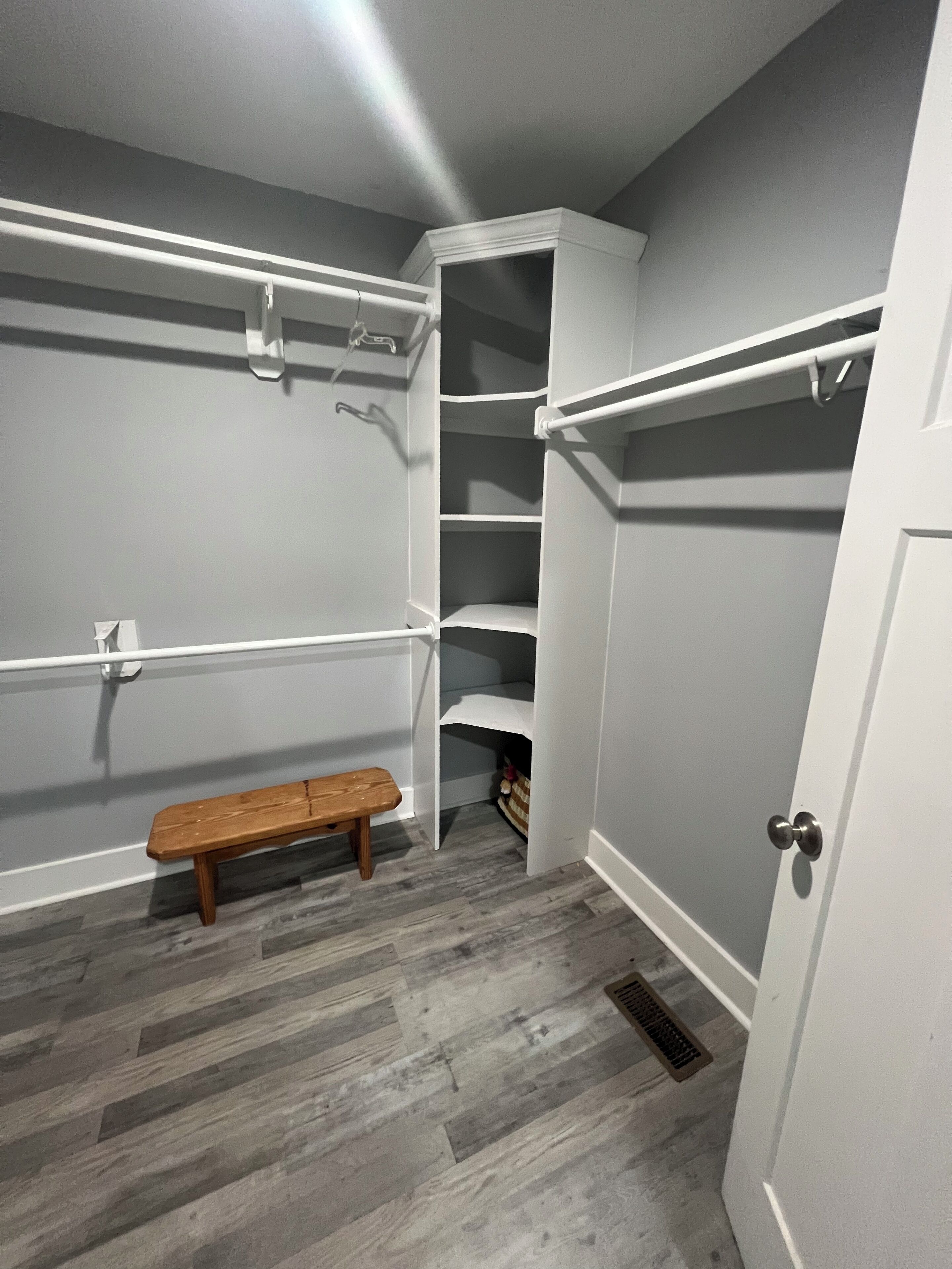 A walk-in closet with open shelving, a bench, and a door.