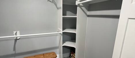 A walk-in closet with open shelving, a bench, and a door.