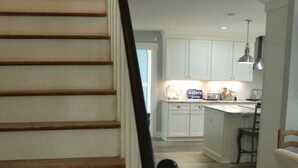 A staircase leading to a kitchen area with white cabinets and a wooden floor.