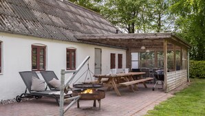 Un patio al aire libre con una chimenea, sillas de descanso y una zona de comedor cubierta.