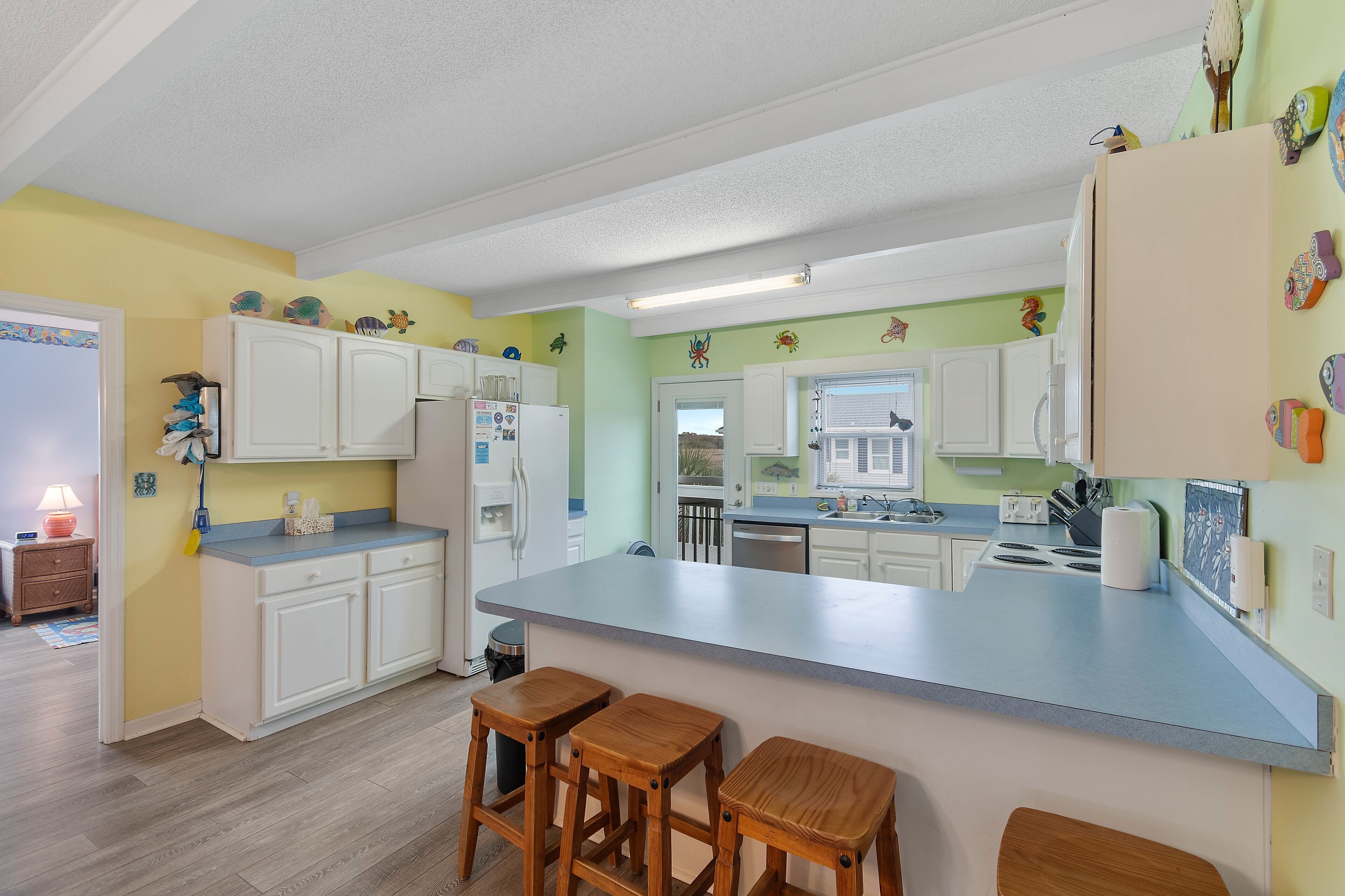 A kitchen with white cabinets, a blue countertop, and wooden stools.