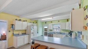A kitchen with white cabinets, a blue countertop, and wooden stools.
