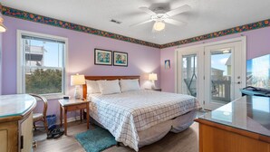 A bedroom with a bed, nightstands, a desk, and a ceiling fan.