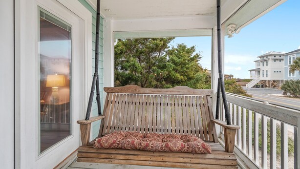 A wooden porch with a bench and a lamp.