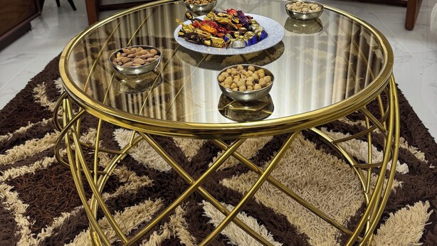 Un salon avec une table basse en verre, deux fauteuils, une petite table d’appoint et une plante en pot.