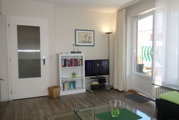 A living room with a bookshelf, a television, and a window with curtains.