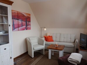 A living room with a sofa, a chair, a coffee table, and a television.