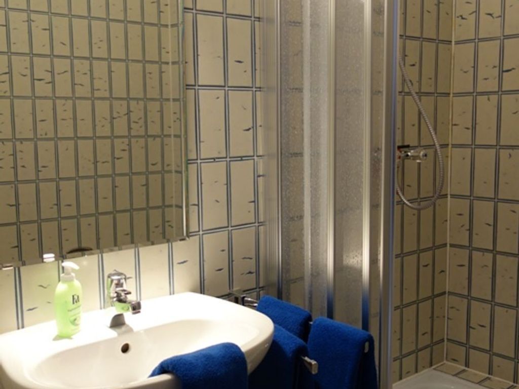 A bathroom with a sink, mirror, and shower.