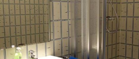 A bathroom with a sink, mirror, and shower.