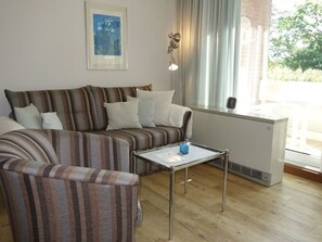 A living room with a striped sofa, a glass coffee table, and a radiator.