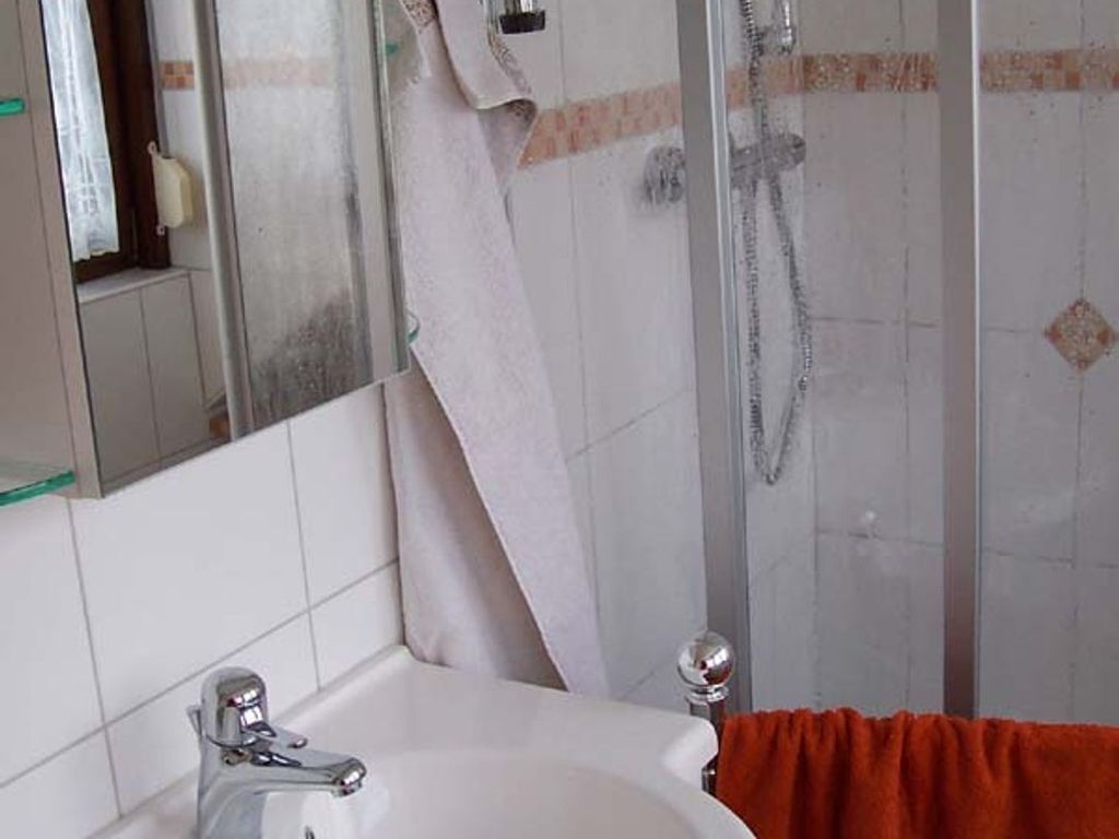 Ein Badezimmer mit Waschbecken, Spiegel und Duschbereich.