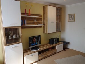 Un espacio habitable compacto con muebles integrados, televisor y objetos decorativos.