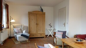 Un salon confortable avec un canapé, un fauteuil, une table en bois et un meuble.
