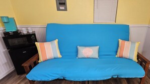 A blue sofa with striped pillows in a room with a microwave and a coffee maker on the counter. - River Bunkie (Tivoli)