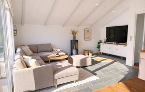 Una sala de estar moderna con un sofá seccional, una mesa de centro, un televisor y una chimenea.