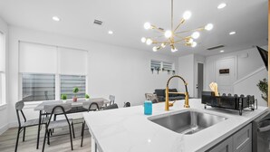 A modern kitchen with a central island, stainless steel sink, and a gold faucet.