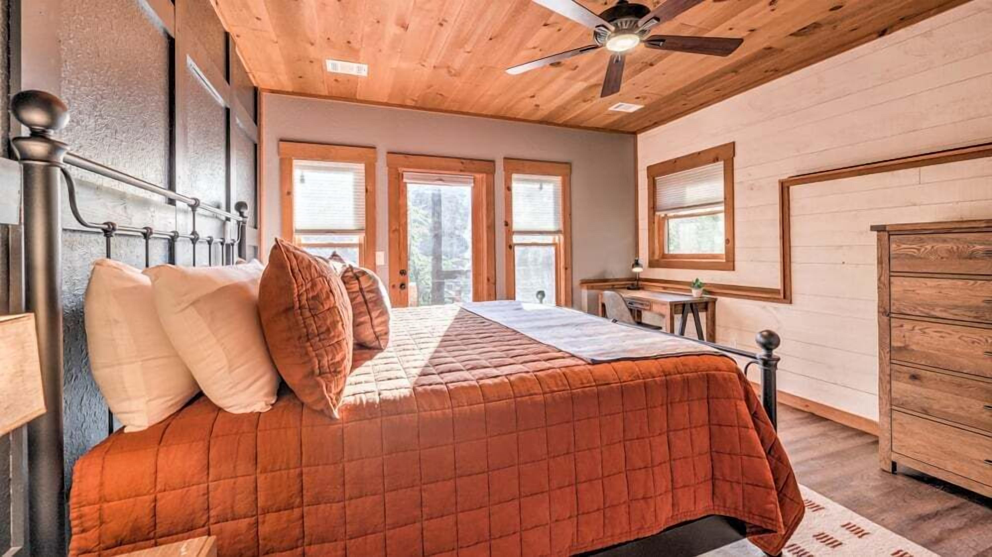 Une chambre à coucher avec un lit, un plafond en bois et un bureau.