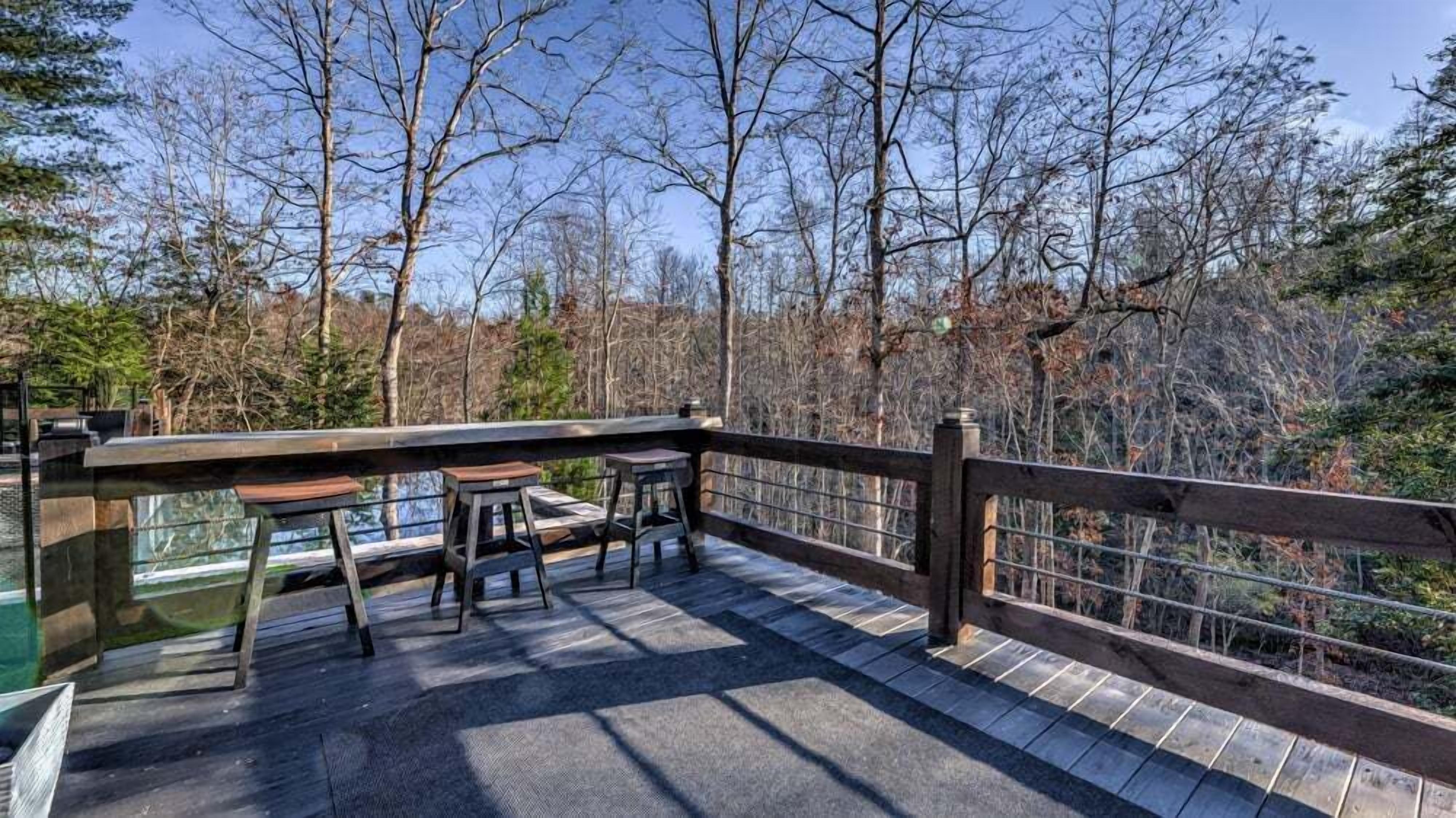 A wooden deck with a table and chairs, overlooking a forested area.