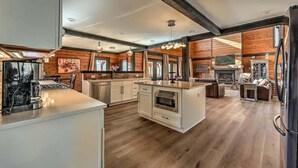 Una cocina moderna con detalles de madera, una isla central y una chimenea en un ambiente acogedor.