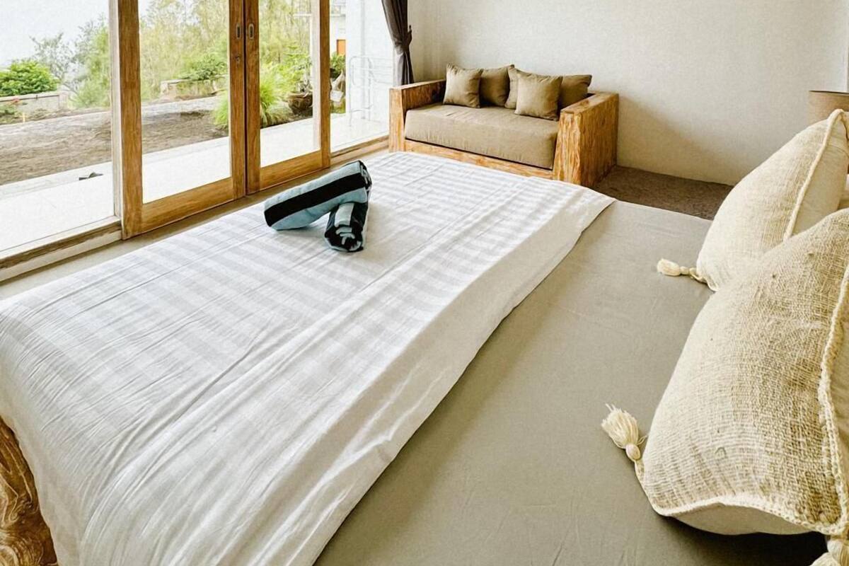 A bedroom with a large bed, a wooden bench, and a sofa.
