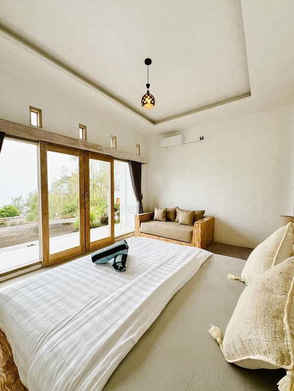 A bedroom with a large bed, a wooden bench, and a sofa.