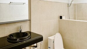 Une salle de bain moderne avec un lavabo noir, des toilettes blanches et un espace douche.