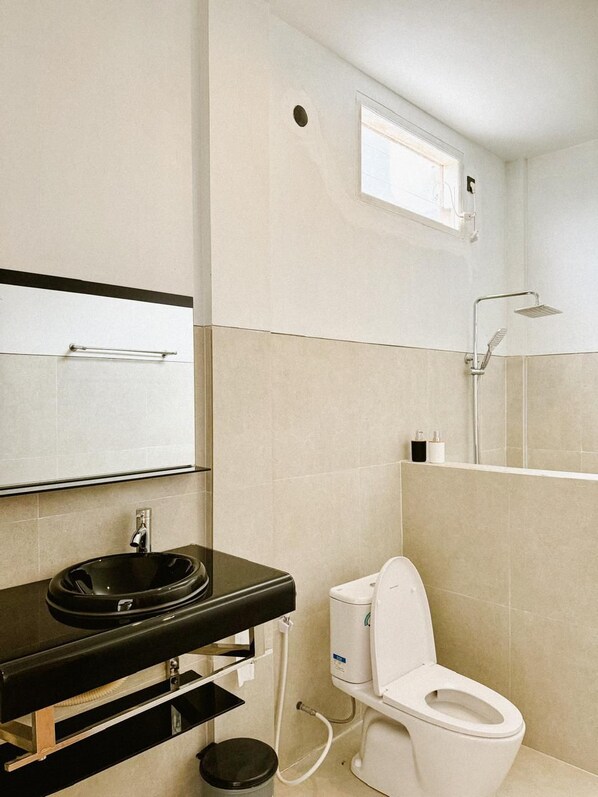 A modern bathroom with a black sink, white toilet, and a shower area. - Batur Exotic (Kintamani)