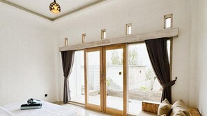 Une chambre moderne avec une grande fenêtre, un cadre de lit en bois, un canapé et un luminaire au plafond.