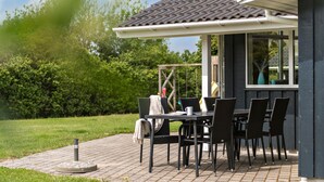An outdoor patio with a table and chairs, a covered seating area, and a view of the surrounding greenery.