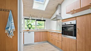 A modern kitchen with wooden cabinets, a built-in oven, and a window with a view of greenery.