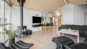 A modern living room with a fireplace, a dining area, and a kitchen in the background.