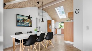 A modern kitchen with wooden cabinets, a white refrigerator, and a window overlooking greenery.
