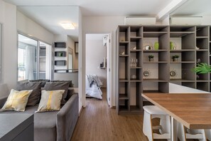 Een moderne woonkamer met een bank, een houten eettafel en inbouwplanken met decoratieve objecten.