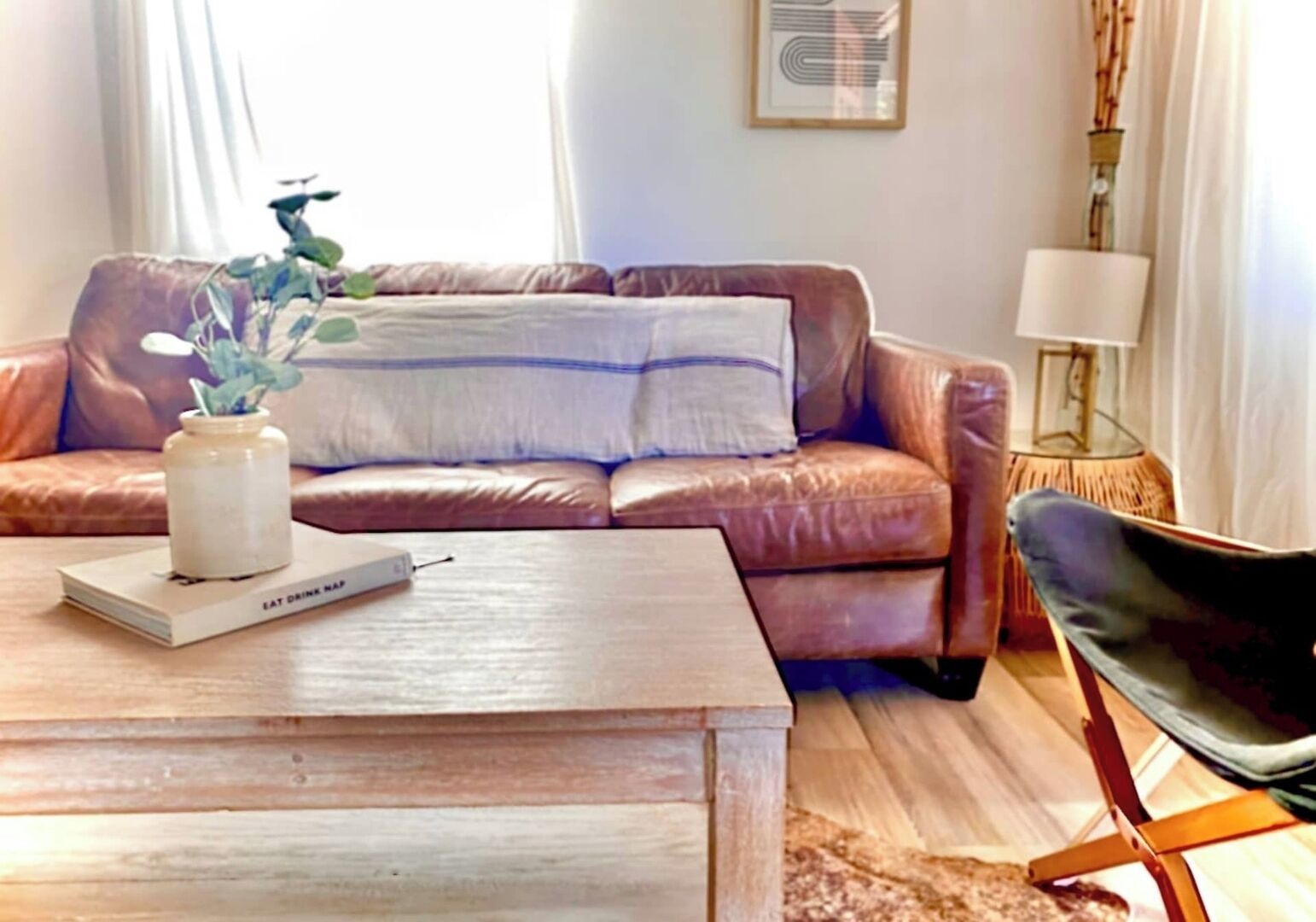Una sala de estar con un sofá de cuero marrón, una mesa de centro de madera y una silla negra.