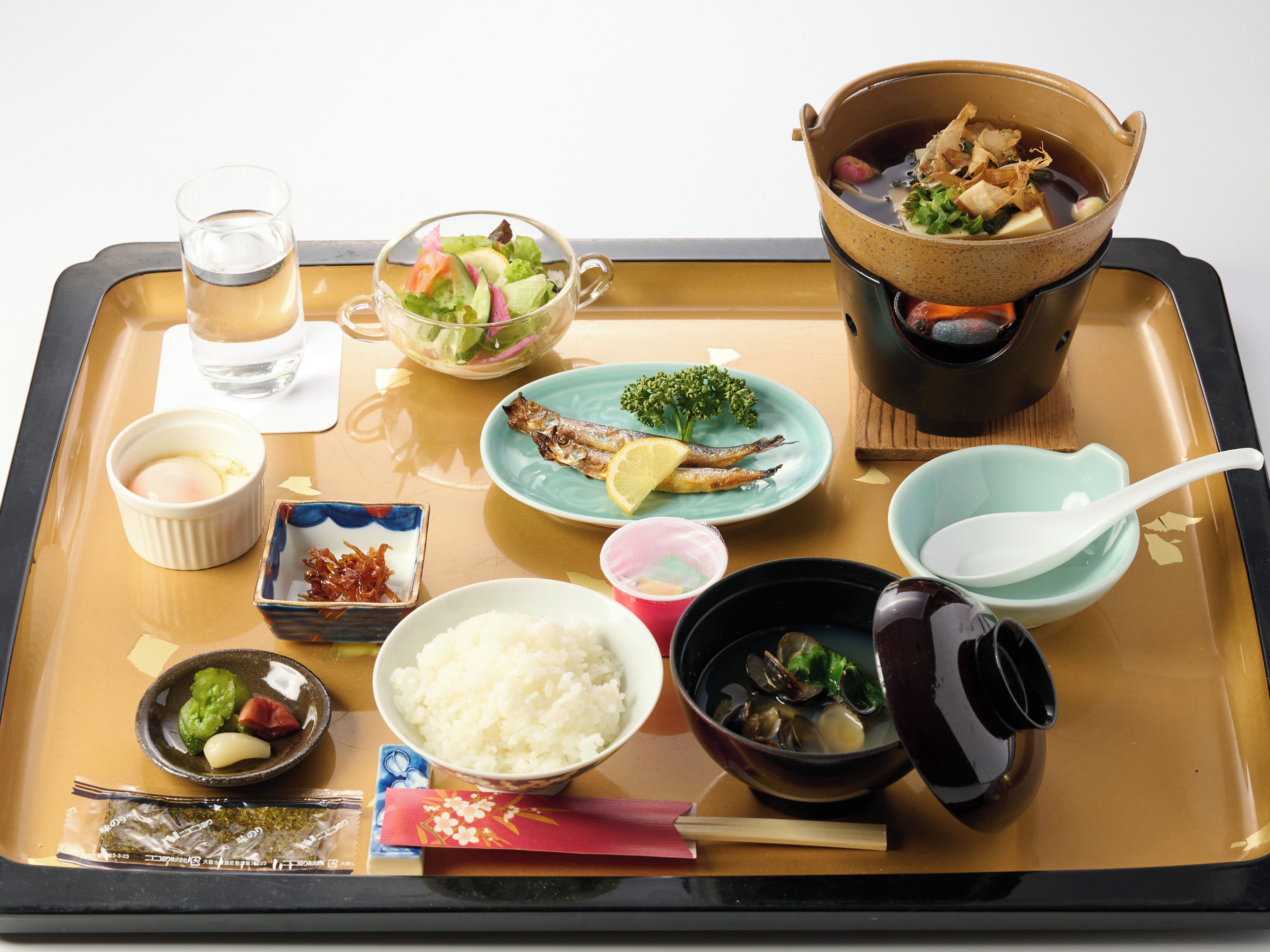 Ein Tablett mit verschiedenen japanischen Gerichten, darunter Reis, Fisch und eine Suppenterrine.