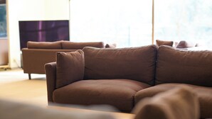 A modern living room with a brown sofa and matching cushions. - Owara View Hotel (Toyama)