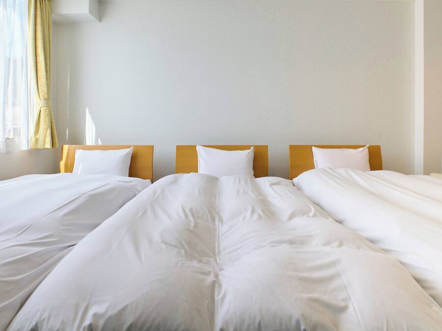 A hotel room with two single beds, each with white bedding and wooden headboards.