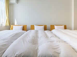 Een hotelkamer met twee enkele bedden, elk met wit beddengoed en houten hoofdeinden.