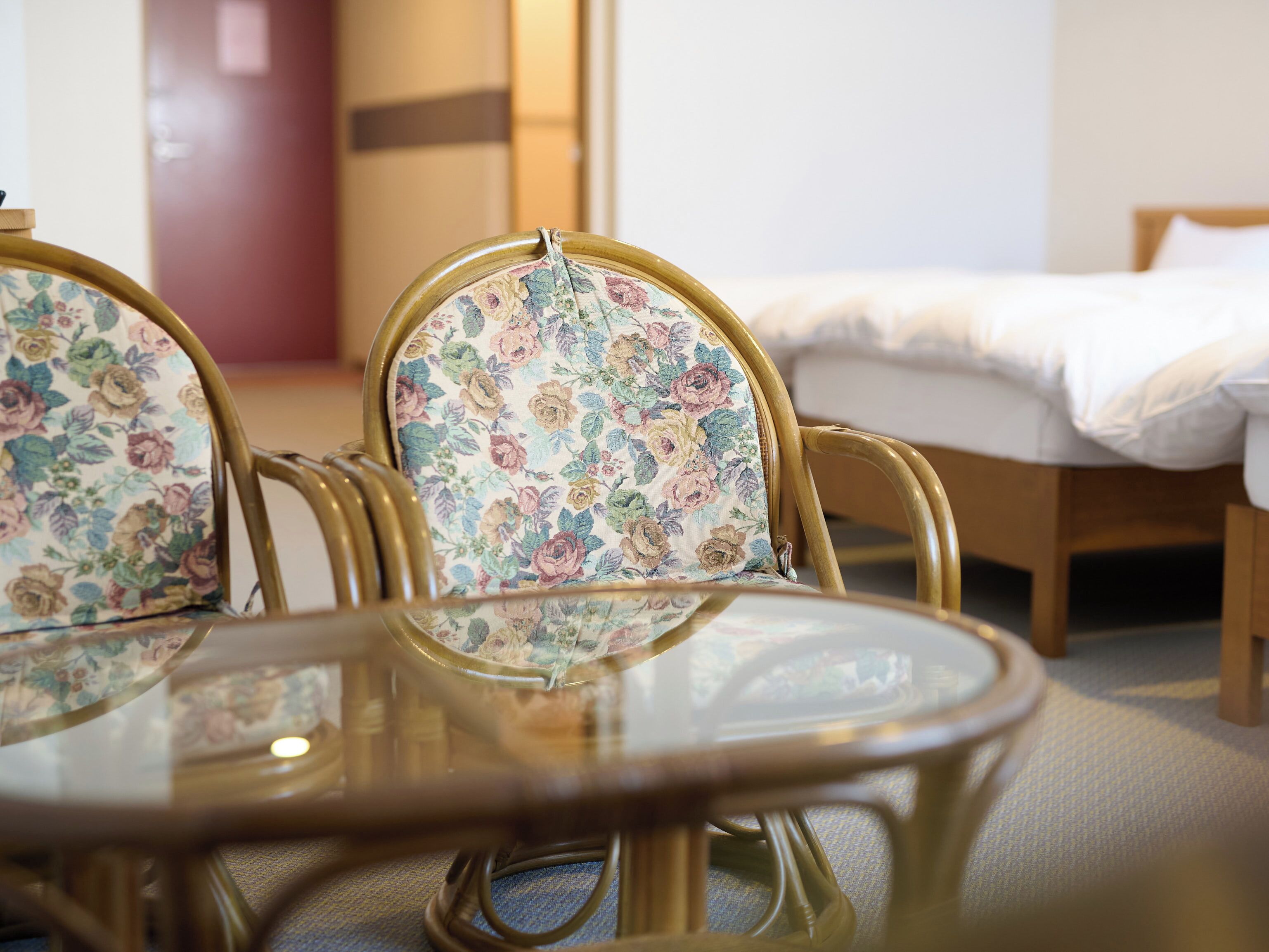 A room with a round glass table and floral upholstered chairs.