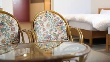 A room with a round glass table and floral upholstered chairs.